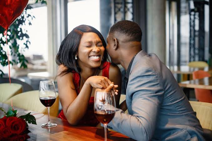 A couple laughing over dinner and red wine on a Valentine's date
