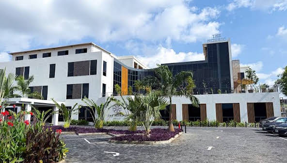 The white and glass frontage of The Nordic Hotel with landscaped parking, Abuja