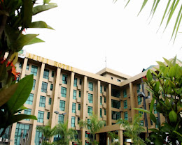 The green-glass facade of Ajuji Greenwich Hotel behind tropical planting