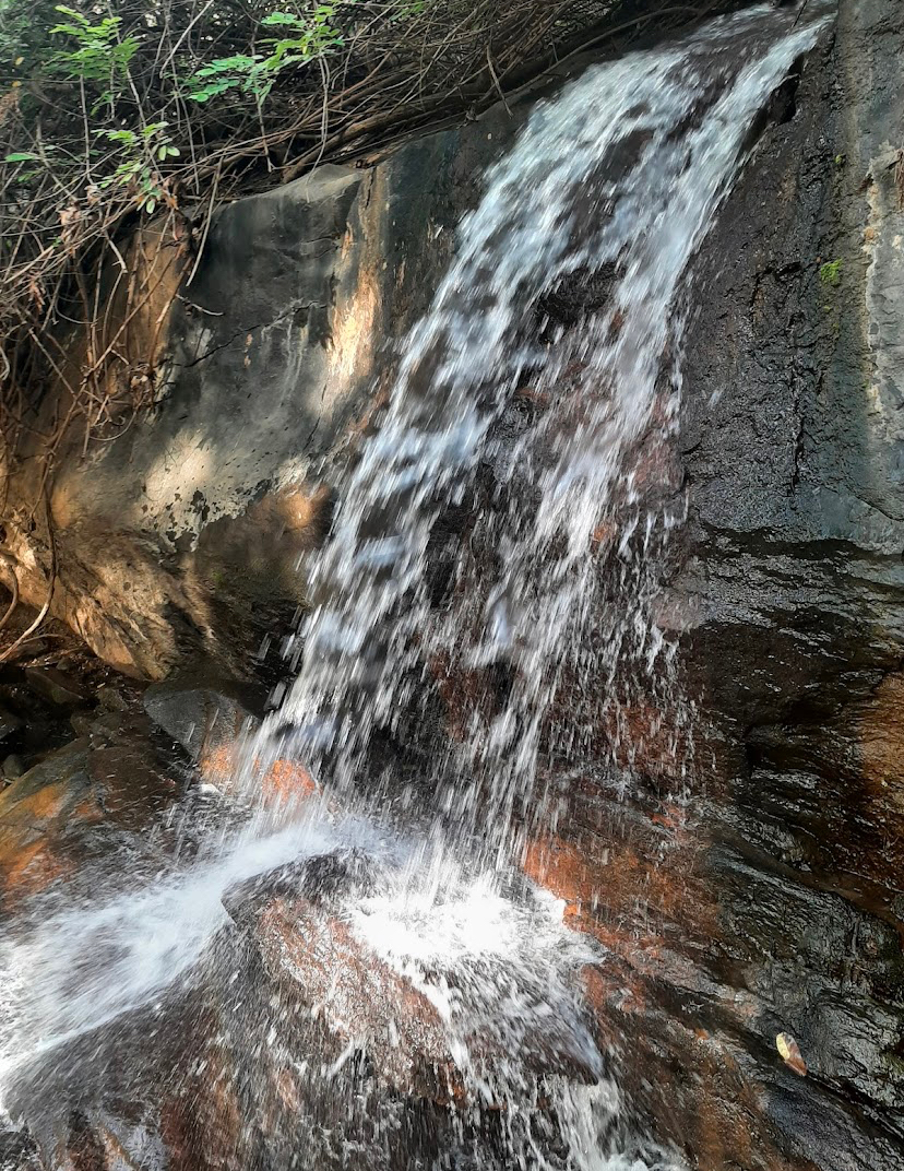 Water cascading over the rocky cliff face at Karu Waterfalls