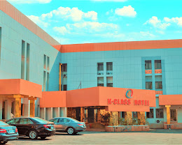 The blue and orange frontage and car park of K-Class Hotel, Abuja