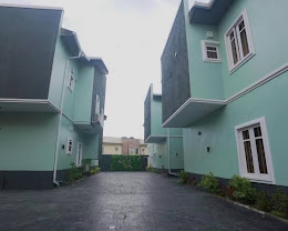 Mint-green duplex apartment blocks along the paved drive at Wallgate Apartments