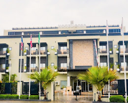The balconied front elevation of Hotel 2020 framed by palm trees, Abuja